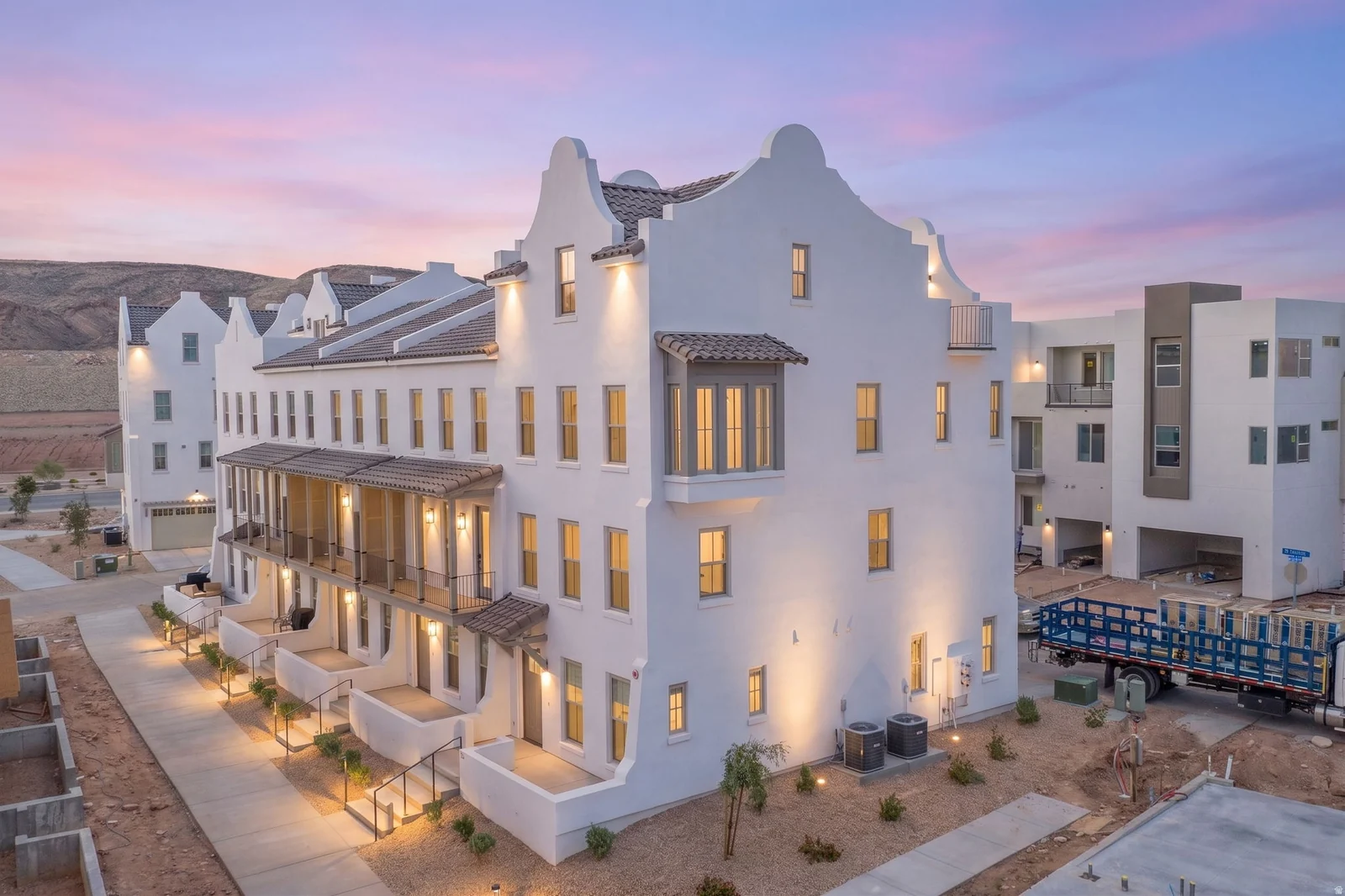 White stucco exterior featuring multiple balconies, a bay window with a tiled roof, and architectural gables